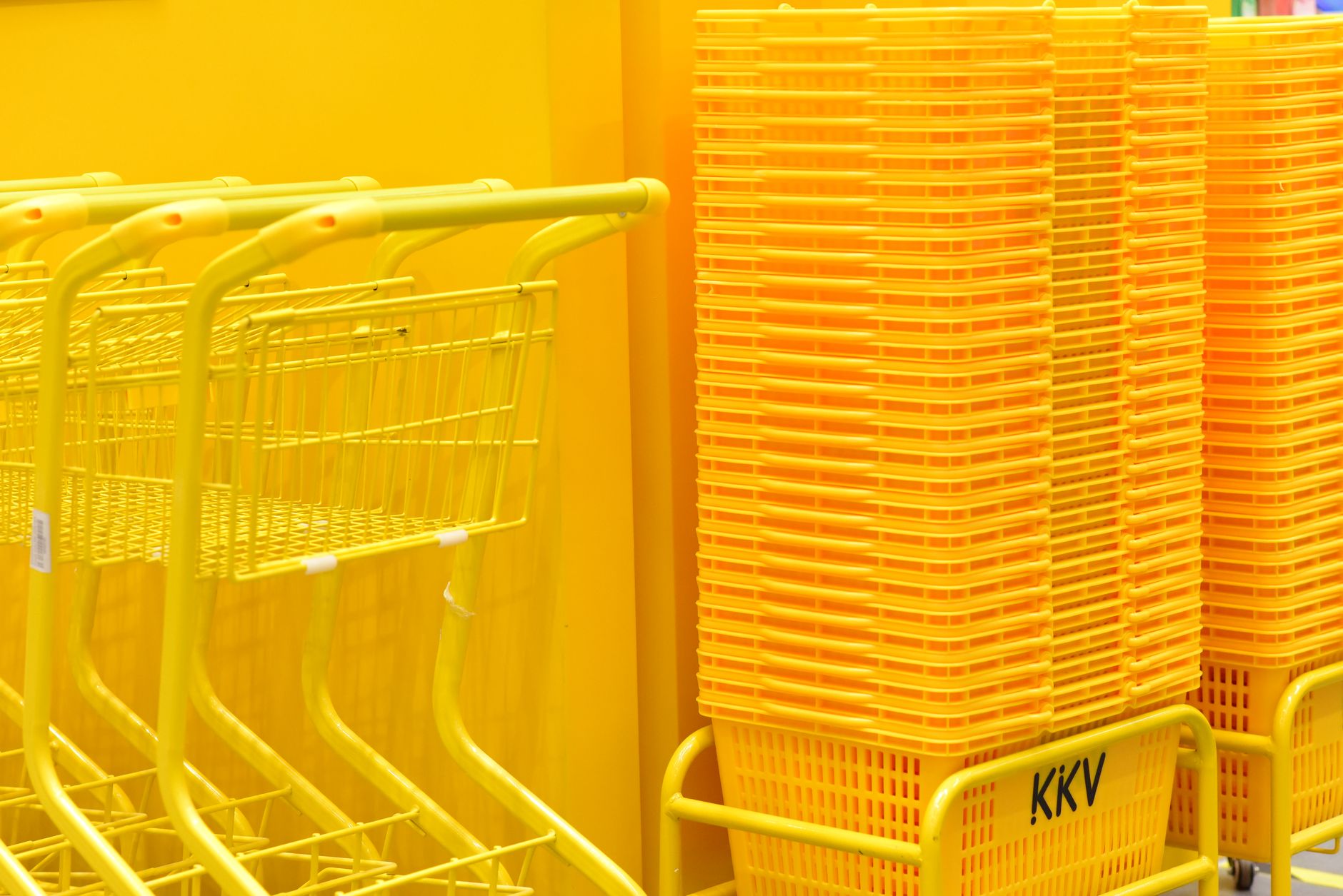 Stacked yellow shopping baskets and a trolley